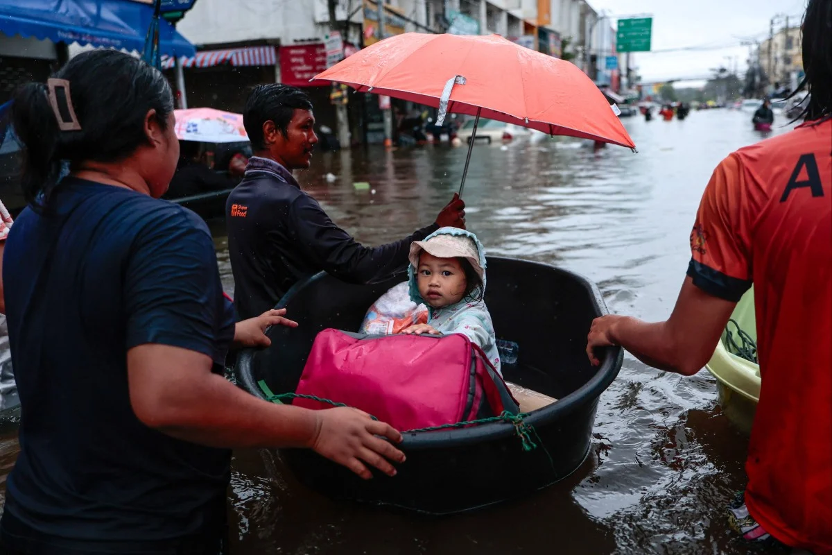 Residents move a child through floodwater in Bangkok